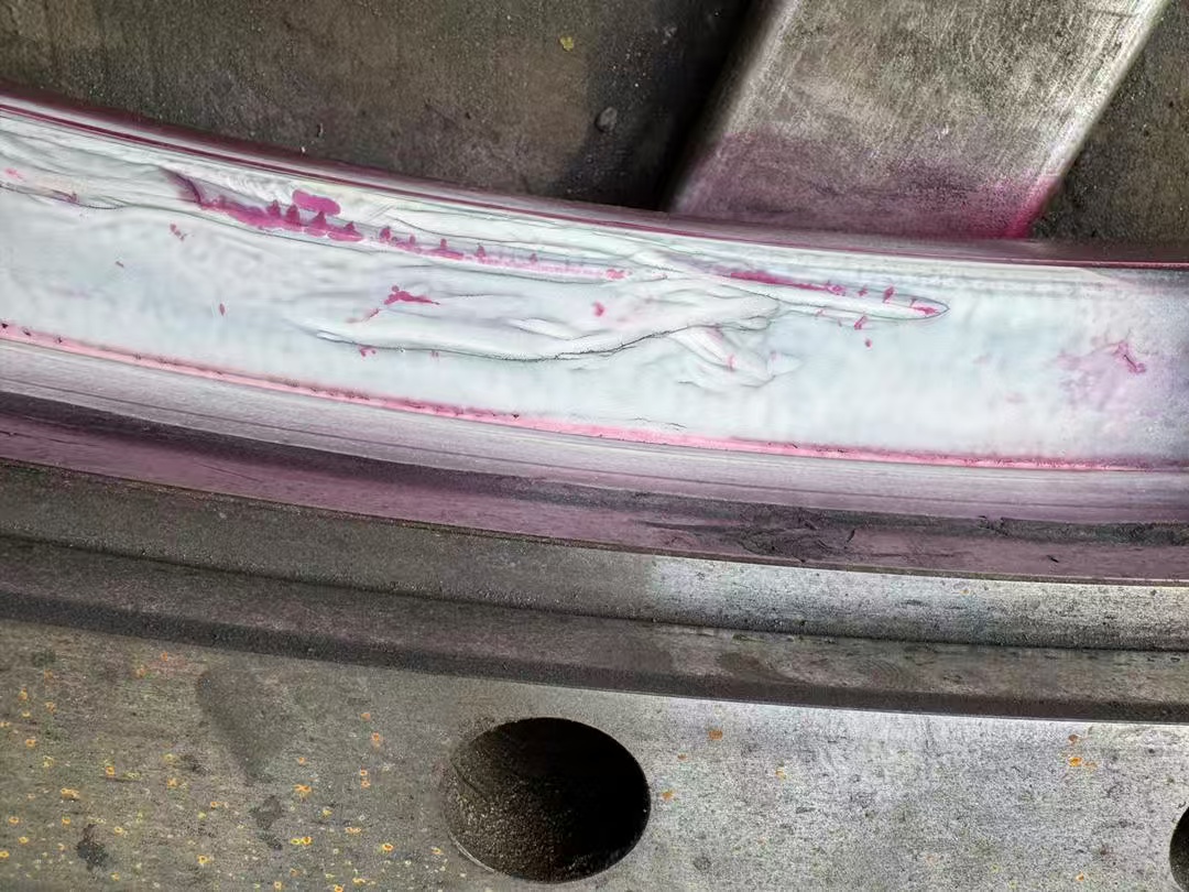 Linear magnetic particle indication along the exposed raceway substrate.