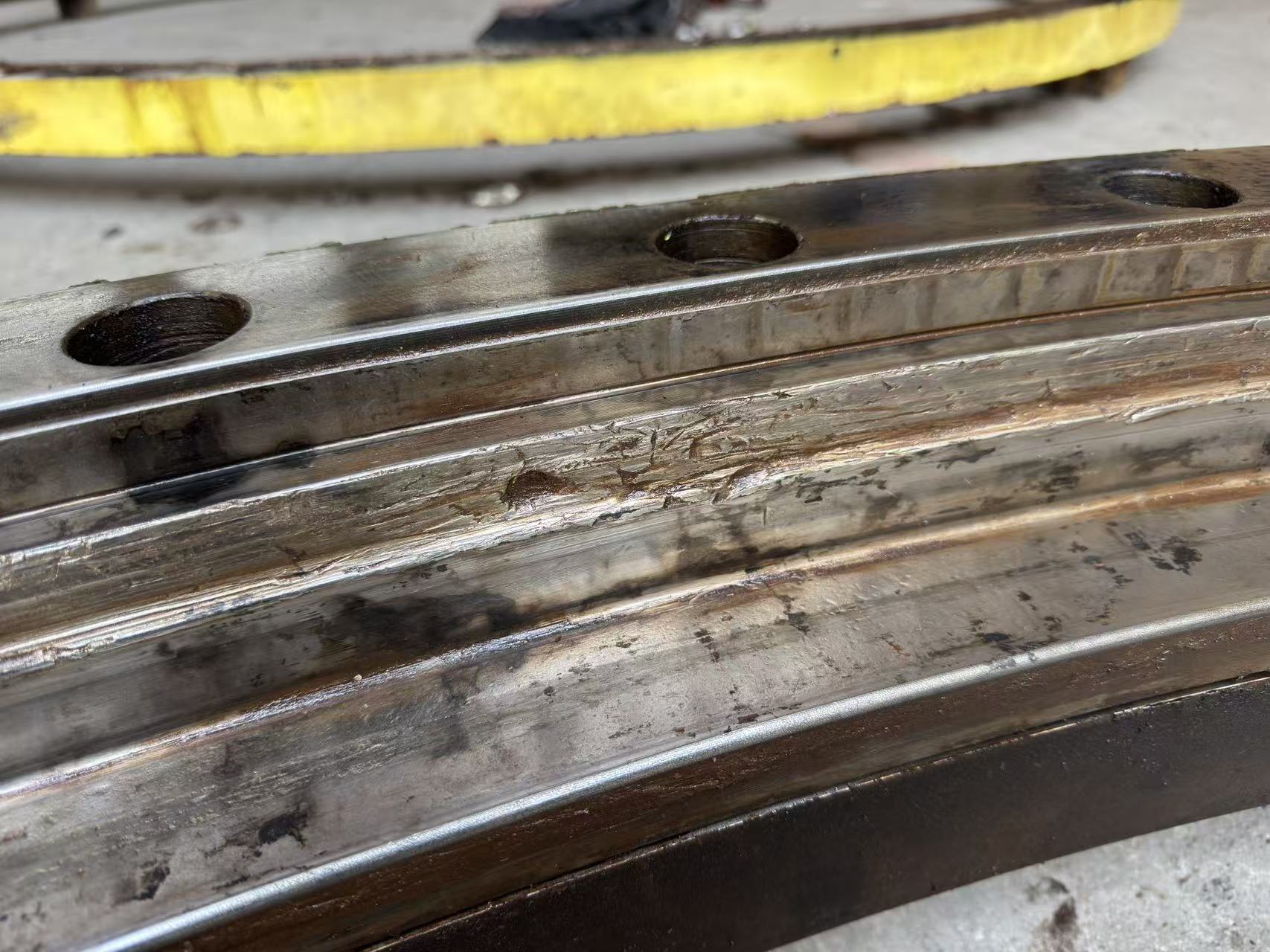 Scored and deformed roller raceway on a damaged slewing bearing ring.